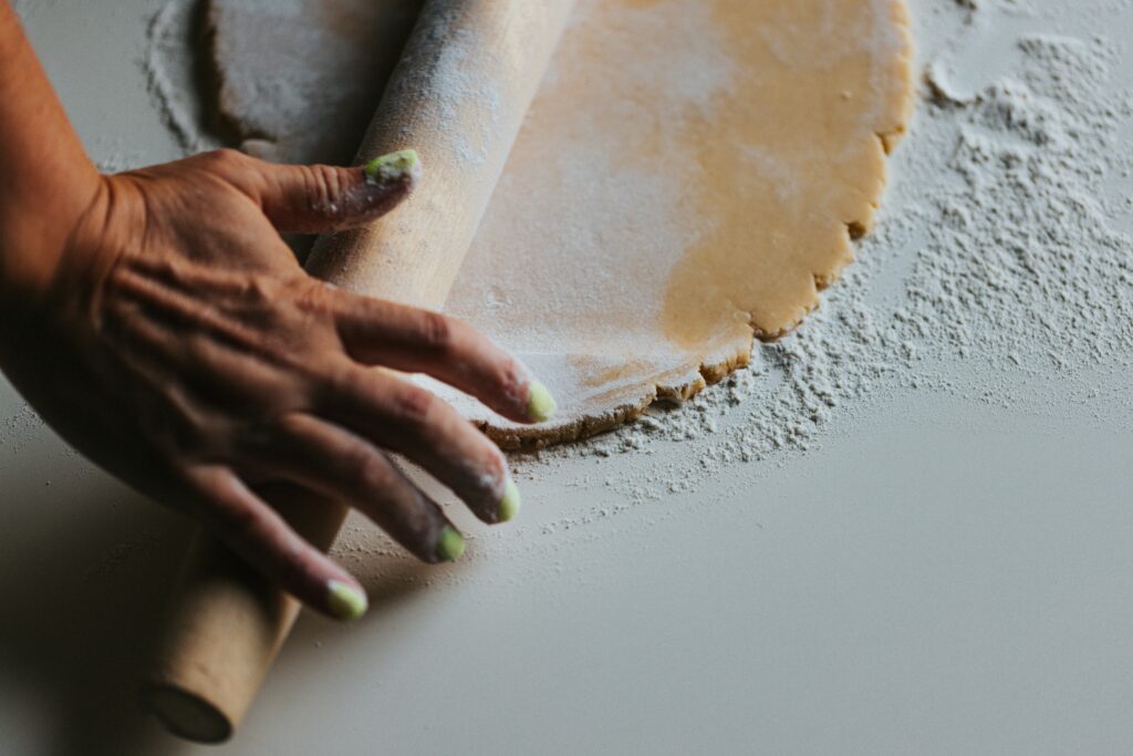 woman is holding a rolling pin over unbaked pie crust in a baking tin