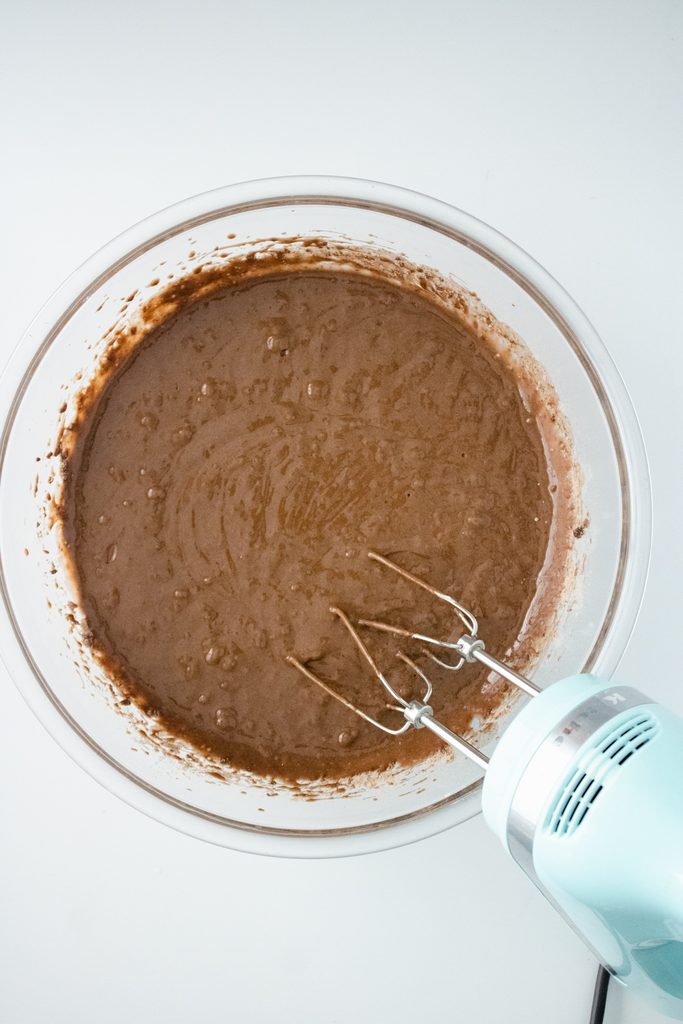 Chocolate cake batter being mixed with a hand mixer