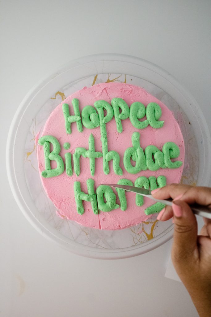 Shallow decorative cracks being added to the pink birthday cake